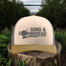 Moco Shirts Guns & Cornbread Richardson 112 snapback hat with tan front, olive brim, and grey mesh back on a tree stump