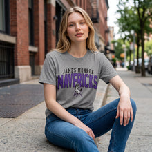 Moco Shirts grey crewneck t-shirt with James Monroe Mavericks mascot logo, worn by a woman on a city sidewalk.